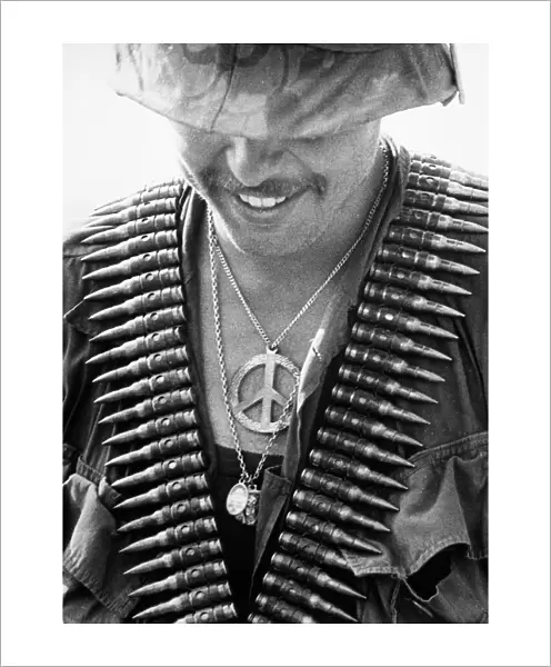 VIETNAM WAR: SOLDIER, 1970. A U. S. 61st Infantry Regiment trooper with a peace symbol and religious medals as well as a bandolier of bullets at Con Thiem, Vietnam, February 1970