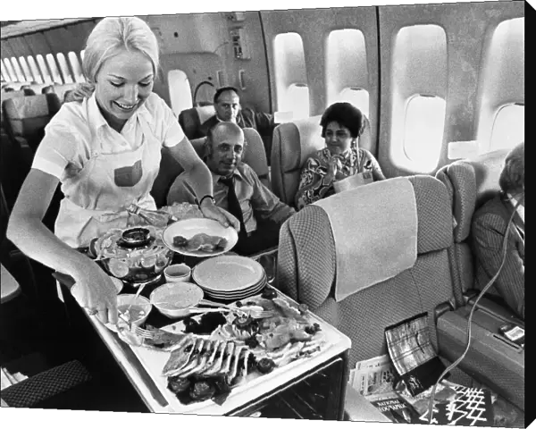 A Pan American flight attendant serves a meal to passengers on board. Photograph, c1975