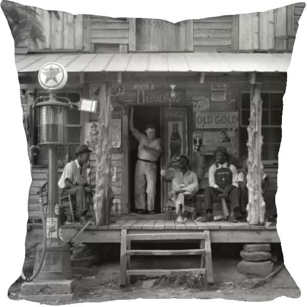 A group of African American men sitting on the porch of a country store, with the owners brother standing in the doorway, on a Sunday afternoon with a kerosene pump on the right and the gasoline pump on the left in Gordonton, North Carolina. Photograph by Dorothea Lange, July 1939. From the Farm Security Administration photography pr