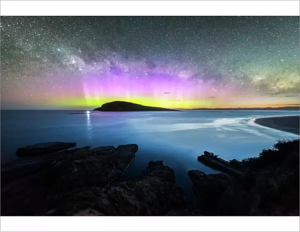 Colourful display of the Aurora Australis over an island in the ocean at Blue Hour
