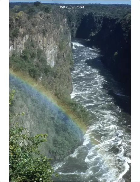 Circa 1955, A rainbow arcs over the gorge of Victoria Falls on the Zambezi River