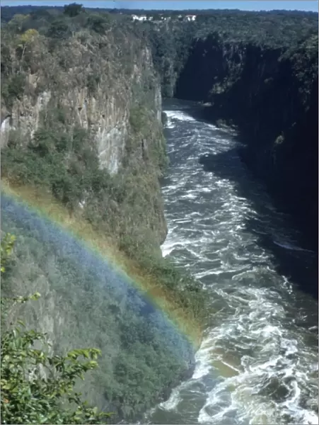 Circa 1955, A rainbow arcs over the gorge of Victoria Falls on the Zambezi River
