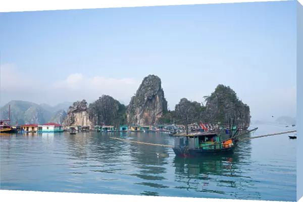Floating Vietnamese fishing village with rocky coastline
