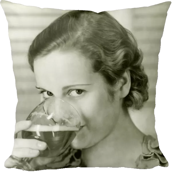 Young woman drinking glass of beer, (B&W), portrait
