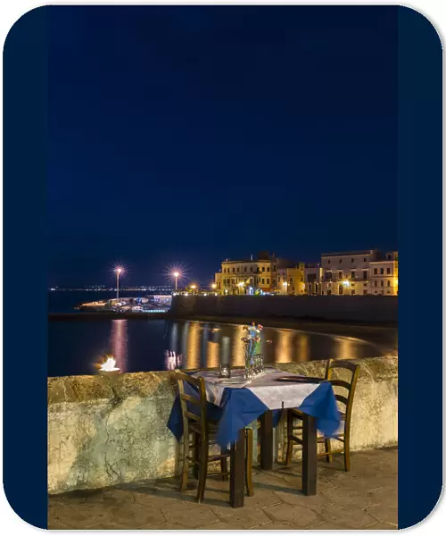 Laid table in restaurant at night, city beach Seno della purita, historic centre, Gallipoli, Province of Lecce, Apulia, Italy