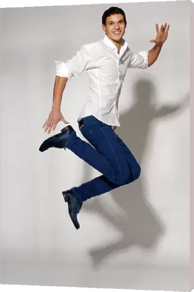 Young man in white shirt and blue jeans jumping