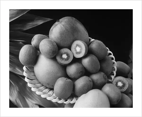 Kiwi fruits and mangos on tray against black background