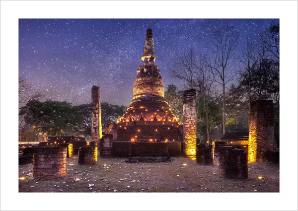 Old stupa with candlelight and milky way galaxy in the Kamphaeng Phet Historical Park