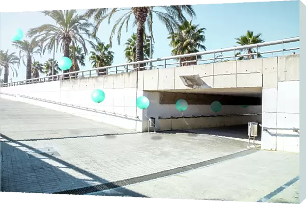 Poetic stop motion picture of green balloons following each other going out from tunnel in a minimal and cool underground pass in the city