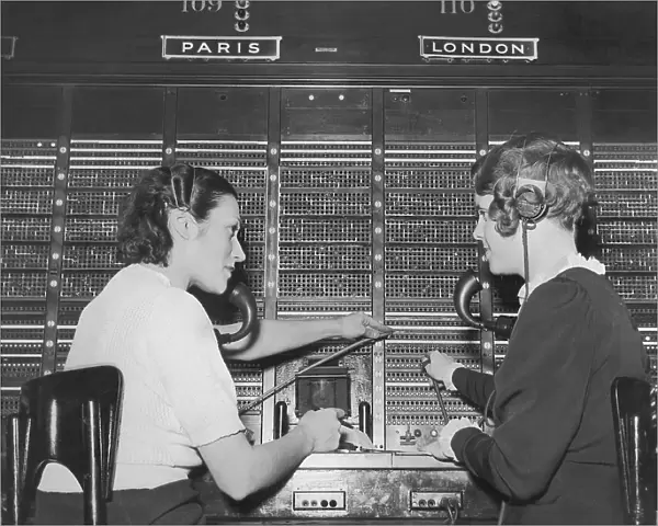 Two female switchboard operators connecting international calls (B&W)