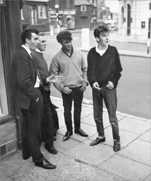 1962 Men standing on a street corner in East Grinstead, West Sussex watching girls go by
