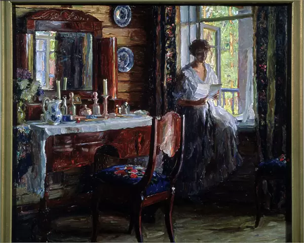 Interieur (Interior). Portrait d'une belle jeune femme assise sur le rebord de la fenetre, lisant une lettre en souriant, pres de sa table de toilette, avec ses produits de soin et de beaute, des bougies et un bouquet de fleurs