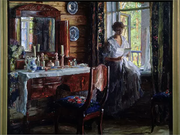 Interieur (Interior). Portrait d'une belle jeune femme assise sur le rebord de la fenetre, lisant une lettre en souriant, pres de sa table de toilette, avec ses produits de soin et de beaute, des bougies et un bouquet de fleurs