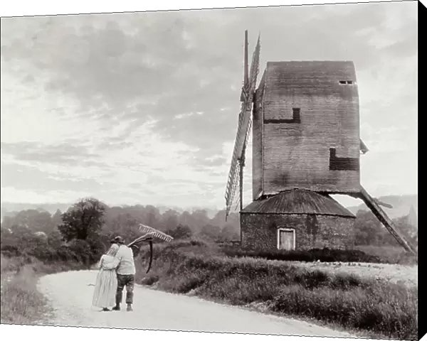 A couple of peasants arm in arm moving down a country path. A windmill can be seen on the right