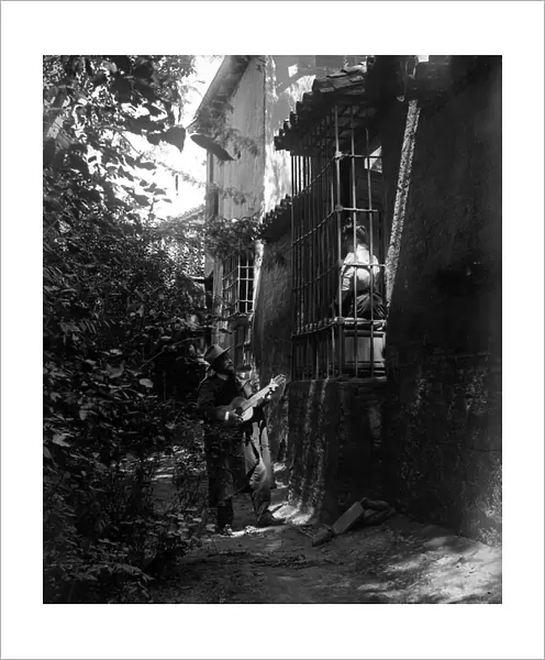 Spain: Tourists play the girl seducted by the guitarist at the feet of her balcony, 1895