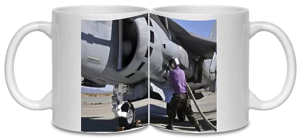 Aviation fuel technician attaches a fuel line to an AV-8B Harrier