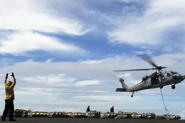 An MH-60S Sea Hawk lifts a pallet of ordnance from the aircraft carrier USS Ronald Reagan