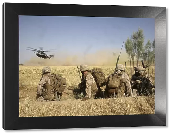 U. S. Marines watch as CH-53E Super Stallion helicopters land in a field