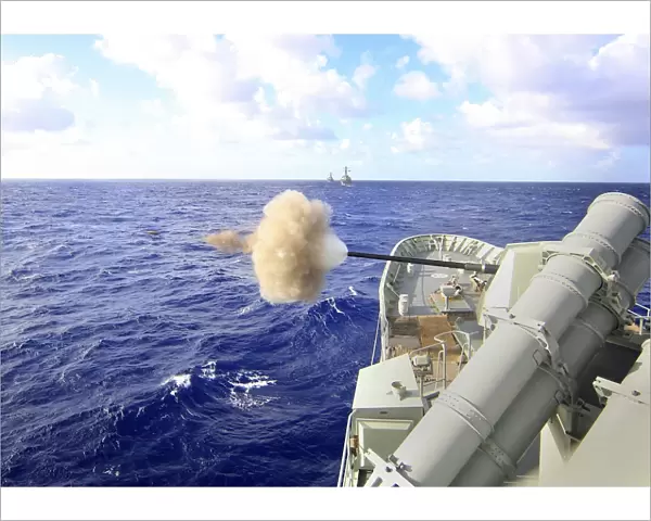 The Australian navy frigate HMAS Warramunga fires its 5-inch gun during a surface