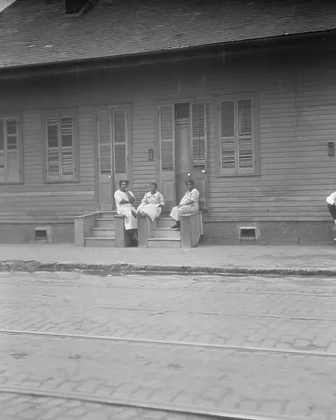 View from across street of three women talking, New Orleans or Charleston, South Ca. c1920-c1926. Creator: Arnold Genthe