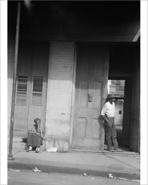 Woman sitting on steps and man standing in a doorway, New Orleans, between 1920 and 1926. Creator: Arnold Genthe