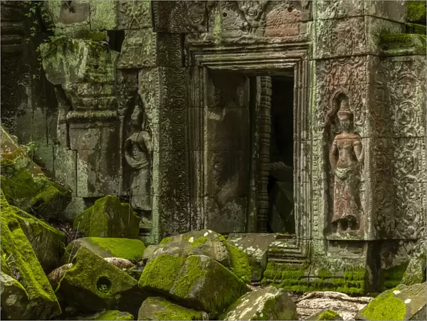 Statues and fallen rocks by temple doorway, Ta Prohm, Angkor Wat, Cambodia
