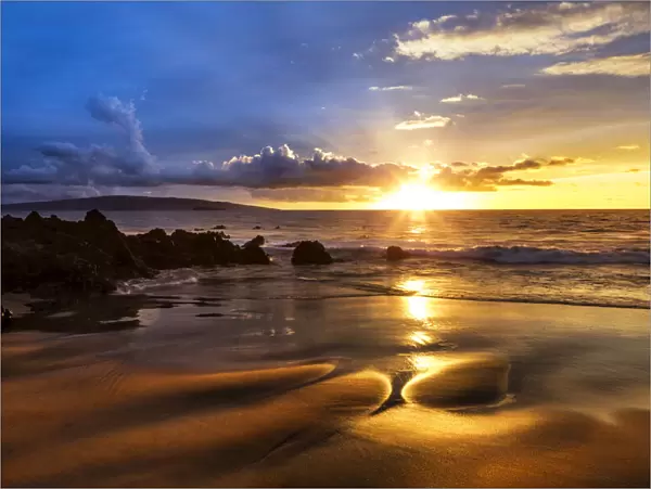 A golden sunset with reflection on sand at on an empty beach, Maui, Hawaii, USA