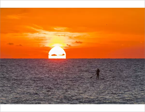 Silhouette of woman paddleboarding on Atlantic Ocean off the coast of Florida at sunrise, USA