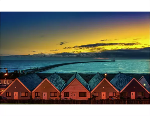 Row of Houses illuminated at sunset with Roker Pier Lighthouse in the distance, Sunderland, England