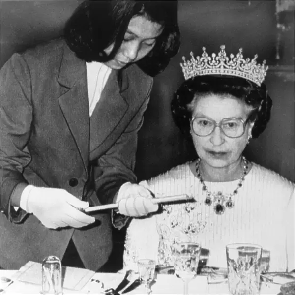 The Queen in China at a banquet in Peking. Being handed chopsticks to eat sea slugs with