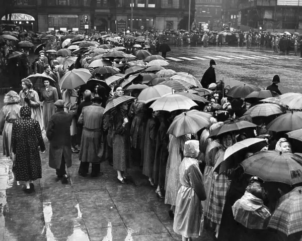 Manchester crowds seek protection from the rain under their umbrellas whilst waiting for