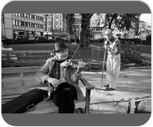 Stephan Grappelli playing his violin in Hanover Square, London watched by park sweeper
