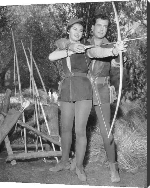 Actor Richard Greene as Robin Hood shows Patricia Driscoll how to use a bow