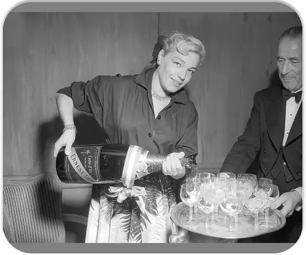 Actress Simone Signoret pouring glasses of champagne at a press conference