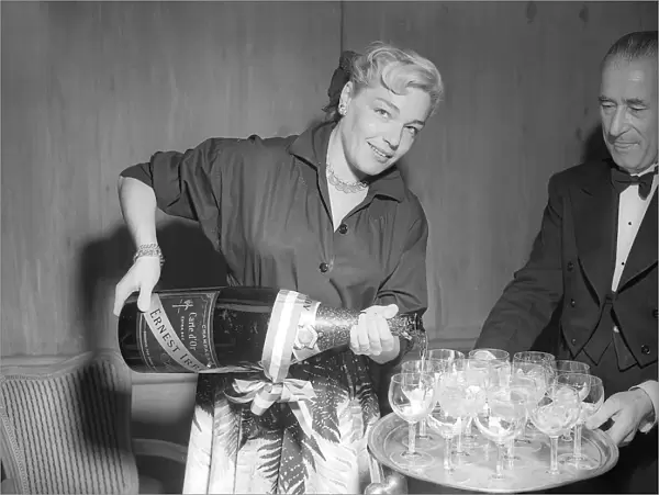 Actress Simone Signoret pouring glasses of champagne at a press conference