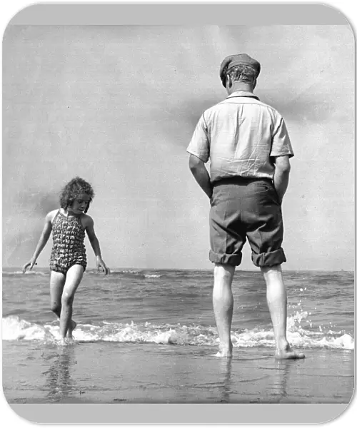 The picture shows a father or grandfather with a little girl on the beach