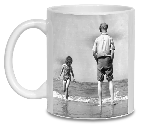 The picture shows a father or grandfather with a little girl on the beach
