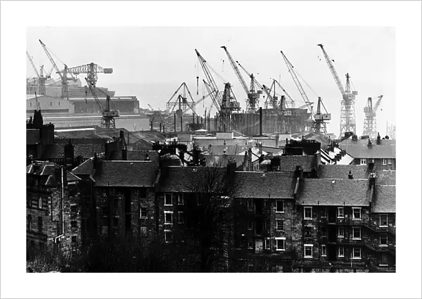 Shipyard cranes rise above tenement apartment buildings by the River Clyde in Scotland