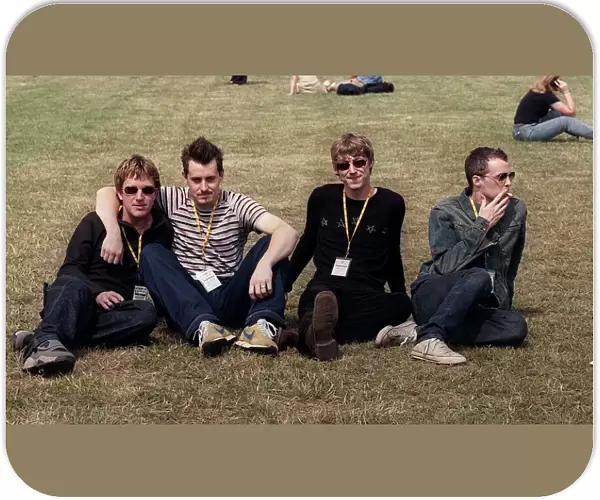 Travis at T in the Park sitting on the grass 2 members are smoking July 1999