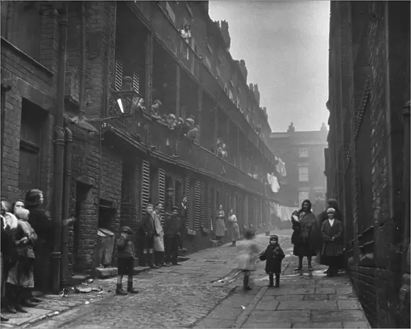 People standing between two terraces in a slum housing area of Liverpool. 2nd March, 1933