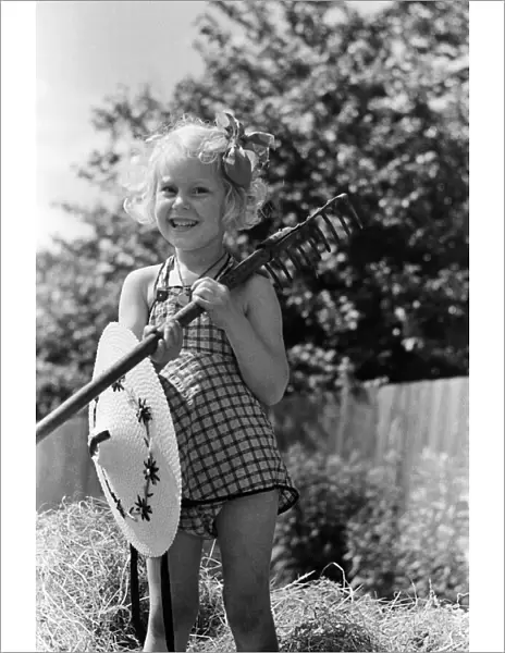 Ella Edwards holding a rake and a sun hat. August 1941
