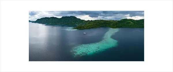 A scenic tropical island is fringed by a healthy coral reef in the Solomon Islands. This beautiful country is home to spectacular marine biodiversity