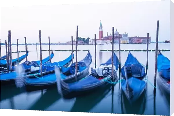 Serene landscape with clear sunrise sky on piazza San Marco in Venice. Row of gondolas parked on city pier