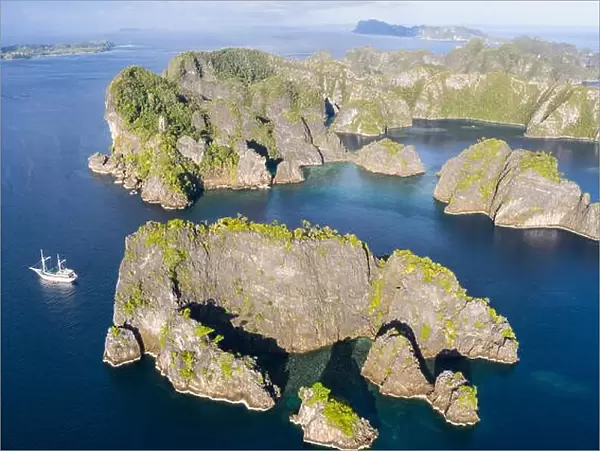 A bird's eye view shows healthy reefs surrounding remote limestone islands in Raja Ampat. This area is known for its incredible marine biodiversity