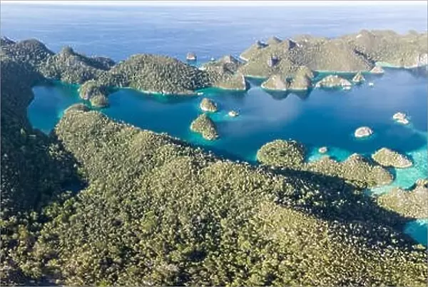 Remote limestone islands form a maze in a tropical lagoon in Raja Ampat, Indonesia. This diverse region is known as the heart of the Coral Triangle