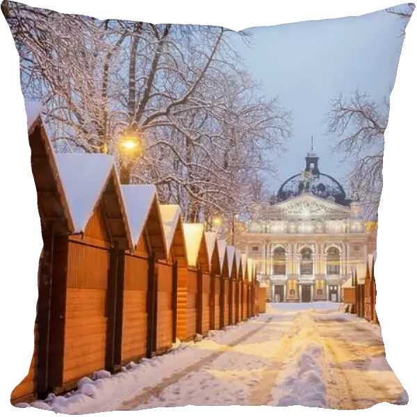 Solomiya Krushelnytska Lviv State Academic Theatre of Opera and Ballet in winter time. Wooden Christmas fair kiosk in a row with city light in