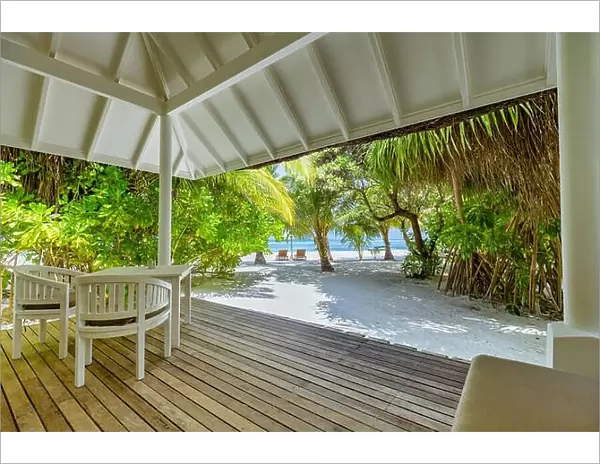 Luxury beach villa, backyard deck with chairs and table. Relaxing beach scene, palm trees, white sand and sea view