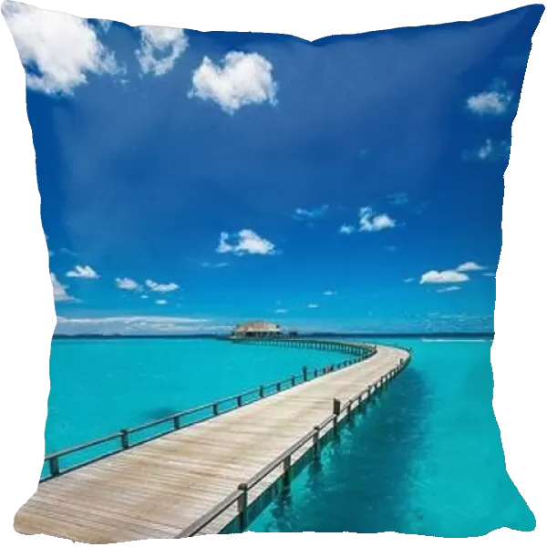 Maldives villa on piles on water, luxury summer travel. Morning sunlight, long wooden jetty under cloudy blue sky. Luxury bungalows, amazing sea