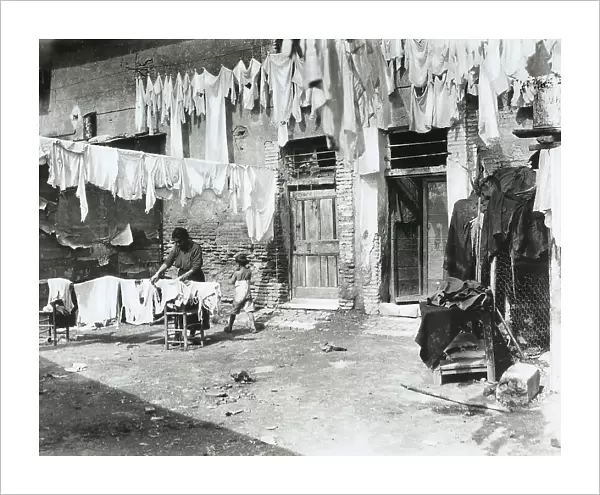 Hanging laundry on the lines of the windows of some houses. A woman is intent on hanging the last items of the laundry. The picture was taken from the courtyard of a house in Rome