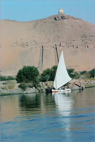 assuan a felucca passing along the coasts where there are some rich tombs of pharaonic lords of the court, on the top the tomb of a Muslim saint